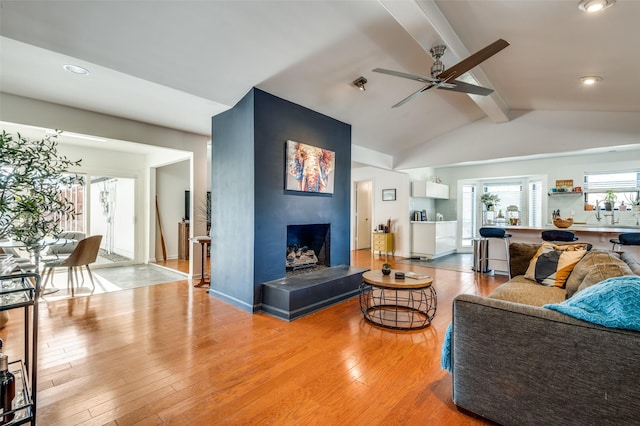 living room featuring wood-type flooring, vaulted ceiling with beams, and ceiling fan