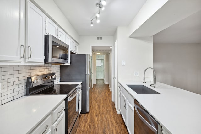 kitchen with dark wood-type flooring, white cabinets, sink, appliances with stainless steel finishes, and tasteful backsplash