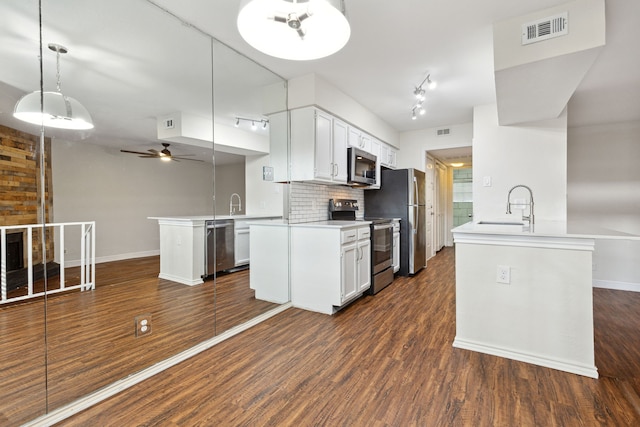 kitchen featuring kitchen peninsula, stainless steel appliances, ceiling fan, white cabinetry, and hanging light fixtures