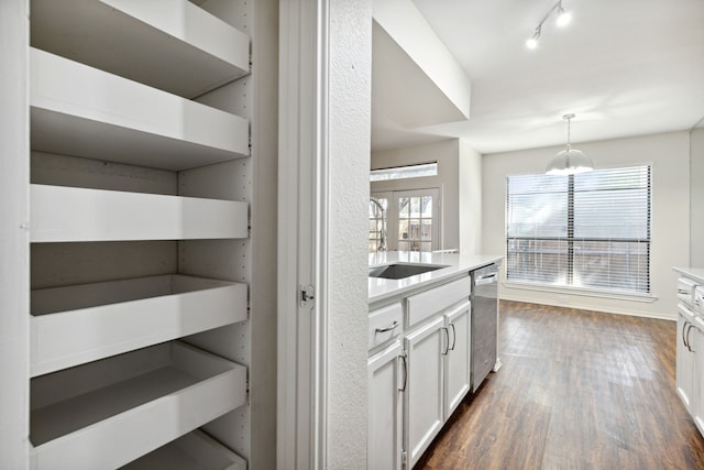 bar featuring sink, dark wood-type flooring, stainless steel dishwasher, pendant lighting, and white cabinets