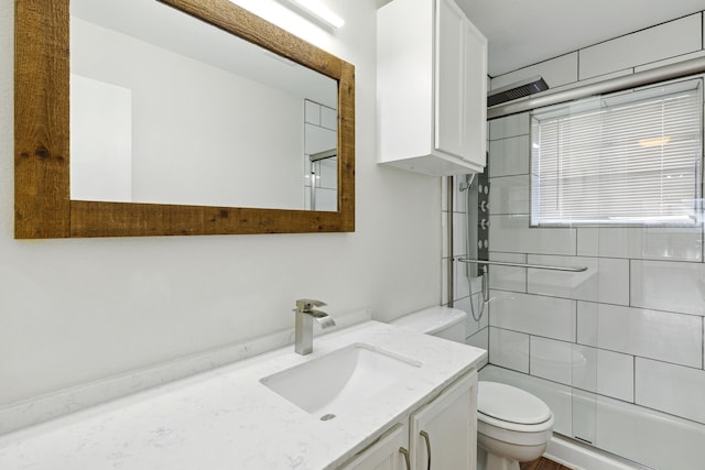 bathroom featuring vanity, toilet, and a shower with door