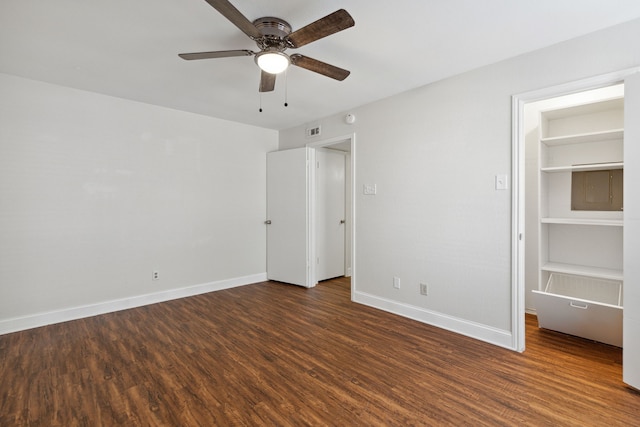 unfurnished bedroom with ceiling fan, dark hardwood / wood-style flooring, a walk in closet, and a closet