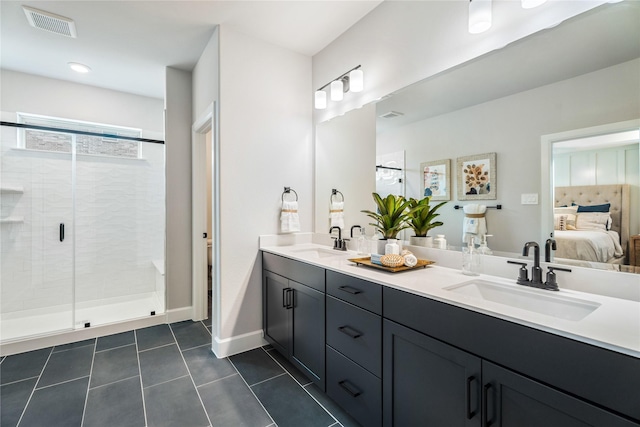 bathroom with a shower with door, vanity, and tile patterned floors