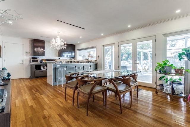 dining area with french doors, an inviting chandelier, light hardwood / wood-style flooring, and sink