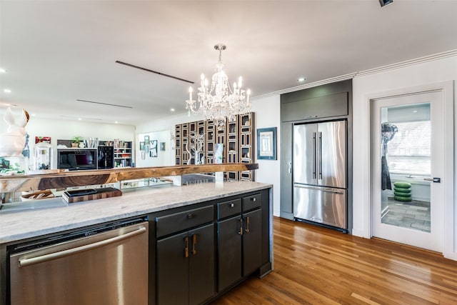 kitchen featuring light stone countertops, stainless steel appliances, pendant lighting, a notable chandelier, and light hardwood / wood-style floors