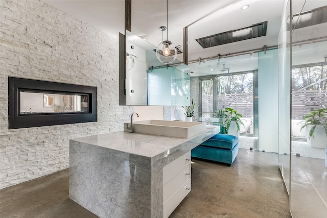 bathroom featuring concrete floors, a stone fireplace, and sink