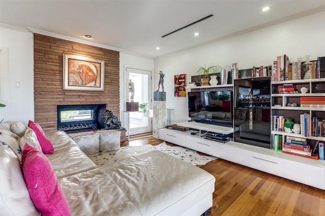 living room with hardwood / wood-style flooring, a stone fireplace, and crown molding