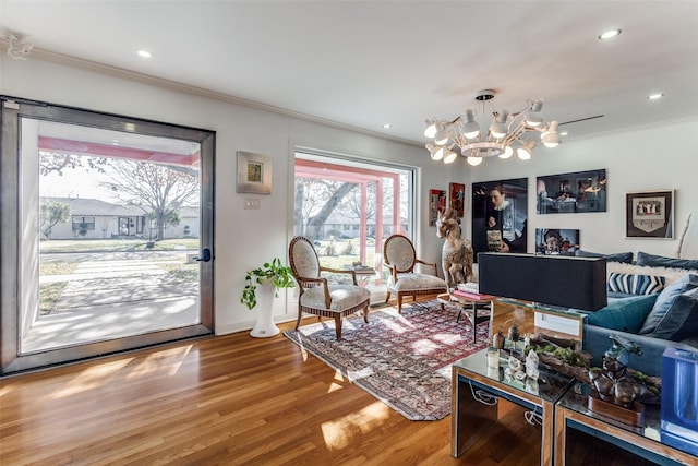 living room featuring a notable chandelier, wood-type flooring, and ornamental molding