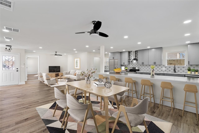 dining area with light hardwood / wood-style floors, sink, and ceiling fan