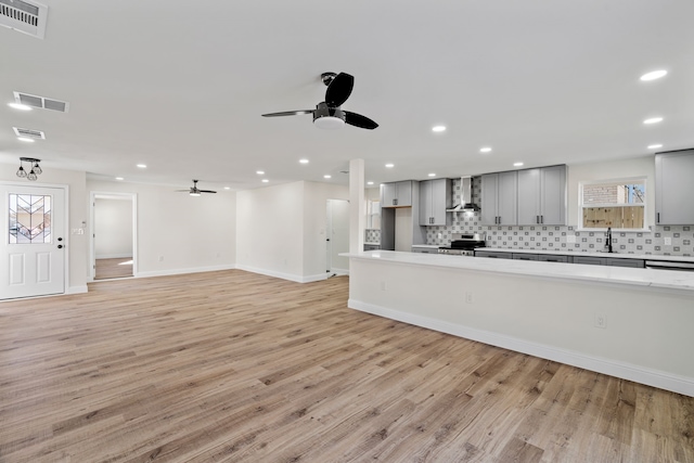 unfurnished living room with light hardwood / wood-style floors, sink, and ceiling fan