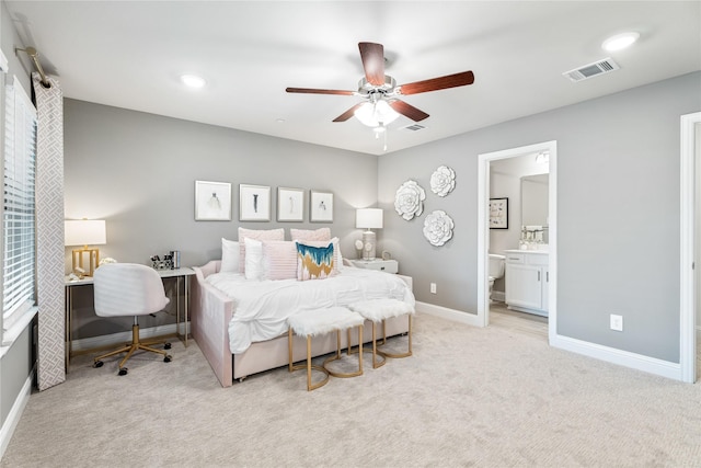 bedroom with light colored carpet, ensuite bath, and ceiling fan