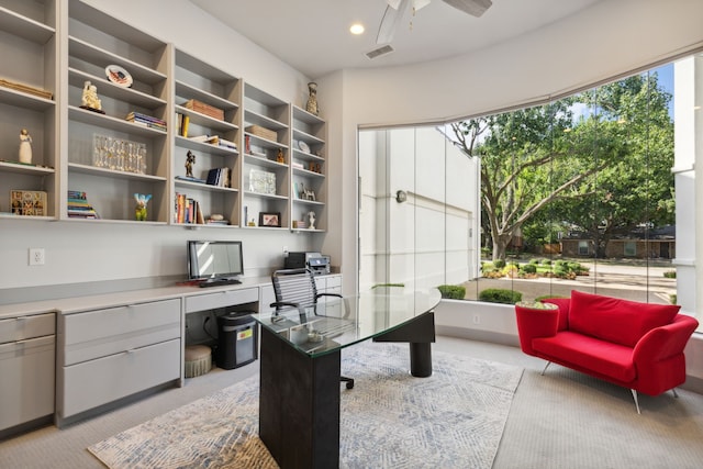 carpeted office featuring plenty of natural light, ceiling fan, and built in desk