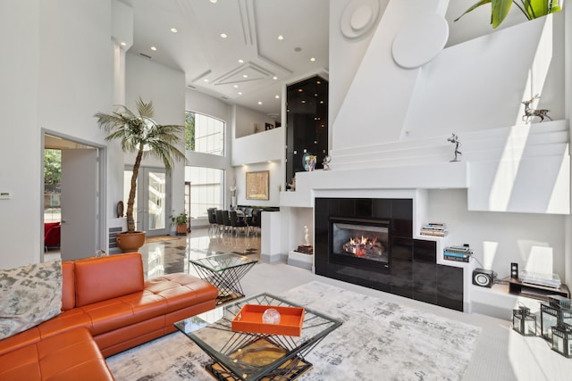 living room with a tile fireplace and a towering ceiling