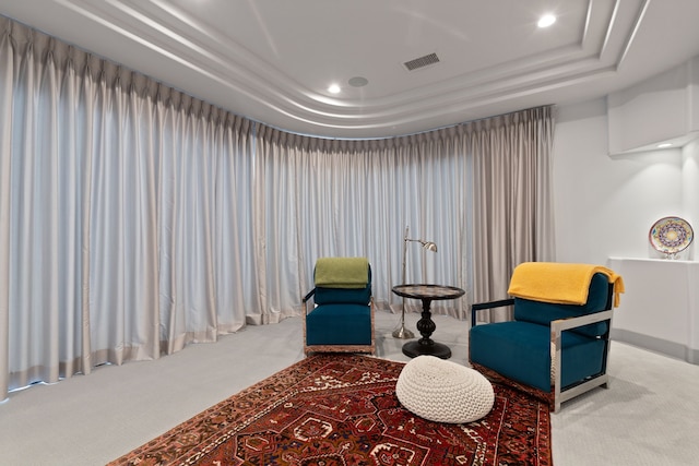 sitting room featuring carpet flooring and a tray ceiling