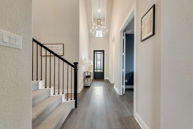 foyer featuring an inviting chandelier, a towering ceiling, and dark hardwood / wood-style floors