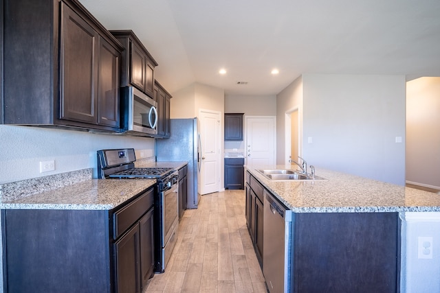 kitchen featuring a kitchen island with sink, sink, light wood-type flooring, dark brown cabinets, and stainless steel appliances