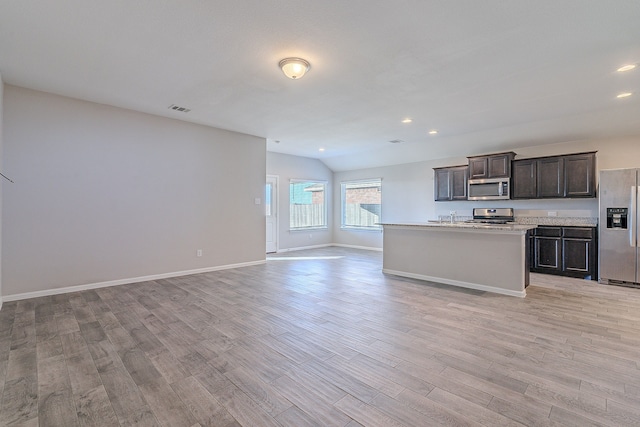 kitchen featuring appliances with stainless steel finishes, light wood-type flooring, a center island with sink, and dark brown cabinets