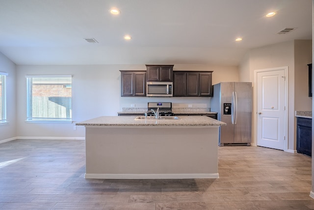 kitchen with a center island with sink, light hardwood / wood-style floors, dark brown cabinetry, and stainless steel appliances