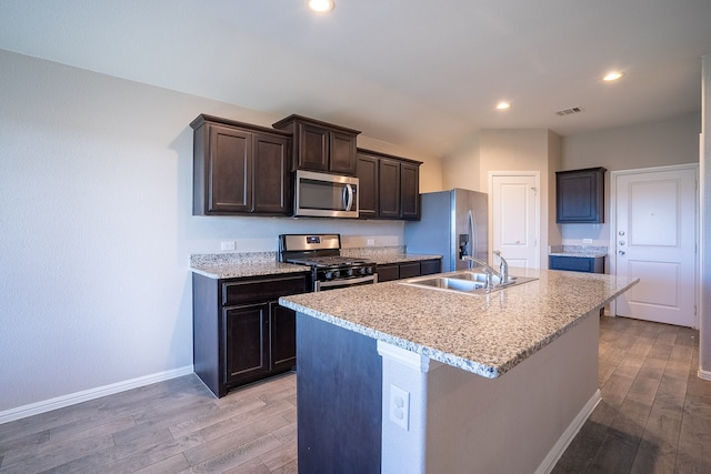 kitchen featuring dark brown cabinets, stainless steel appliances, sink, hardwood / wood-style floors, and an island with sink