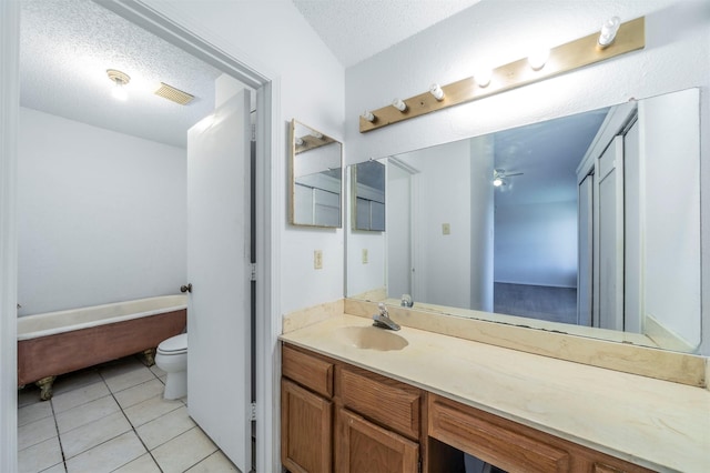 bathroom with tile patterned floors, ceiling fan, toilet, a textured ceiling, and vanity