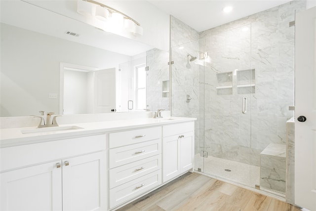 bathroom featuring an enclosed shower, vanity, and wood-type flooring