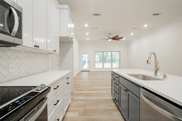 kitchen featuring stainless steel appliances, white cabinets, decorative backsplash, and sink