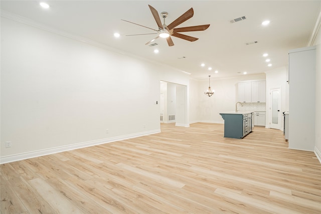 unfurnished living room featuring ceiling fan with notable chandelier, sink, light hardwood / wood-style floors, and crown molding