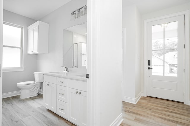 bathroom featuring toilet, an enclosed shower, vanity, and hardwood / wood-style flooring