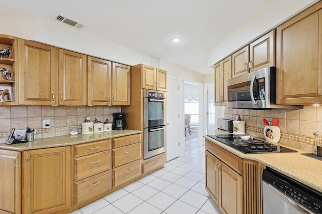 kitchen featuring light stone counters, appliances with stainless steel finishes, light tile patterned flooring, and backsplash