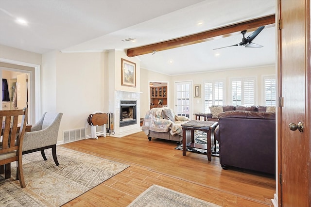 living room with ceiling fan, a premium fireplace, lofted ceiling with beams, and hardwood / wood-style flooring