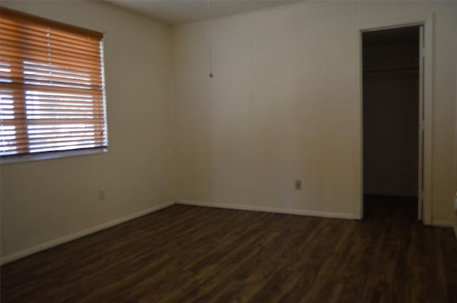 unfurnished bedroom with dark hardwood / wood-style flooring, a spacious closet, and a closet