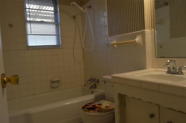 full bathroom featuring tile walls, sink, tiled shower / bath combo, and toilet