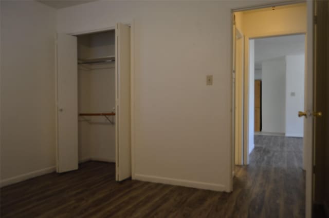 unfurnished bedroom with a closet and dark hardwood / wood-style flooring