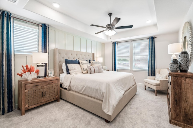 carpeted bedroom featuring a raised ceiling and ceiling fan