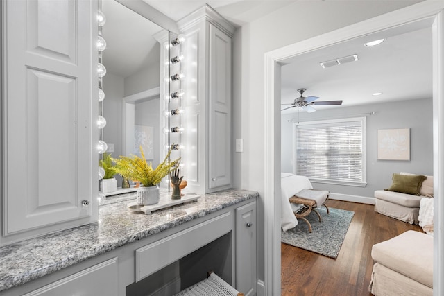 bar with light stone countertops, dark wood-type flooring, ceiling fan, and white cabinetry