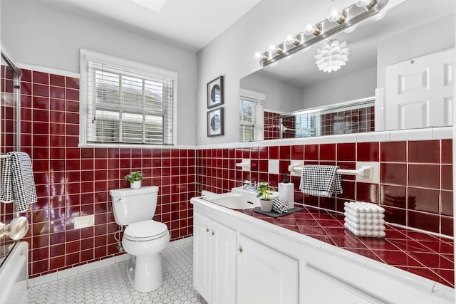 full bathroom with toilet, combined bath / shower with glass door, tile walls, tile patterned floors, and vanity