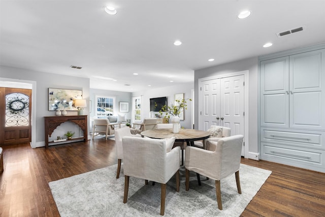 kitchen with stainless steel appliances, an island with sink, light stone countertops, dark wood-type flooring, and sink