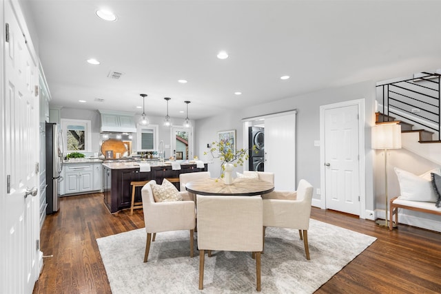 dining area featuring stacked washer and clothes dryer, sink, and dark hardwood / wood-style floors