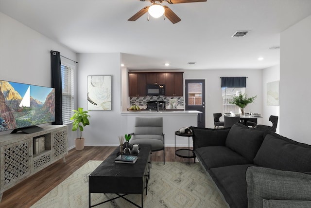 living room featuring ceiling fan, a wealth of natural light, dark hardwood / wood-style floors, and sink