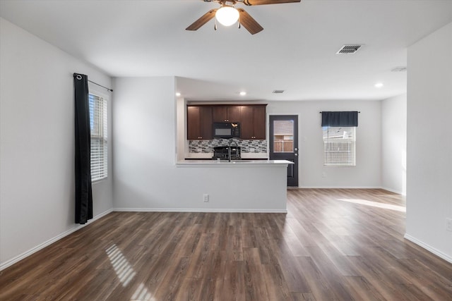 unfurnished living room with dark wood-type flooring, ceiling fan, and sink