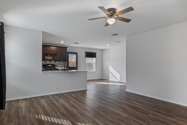 unfurnished living room with ceiling fan, sink, and dark hardwood / wood-style flooring