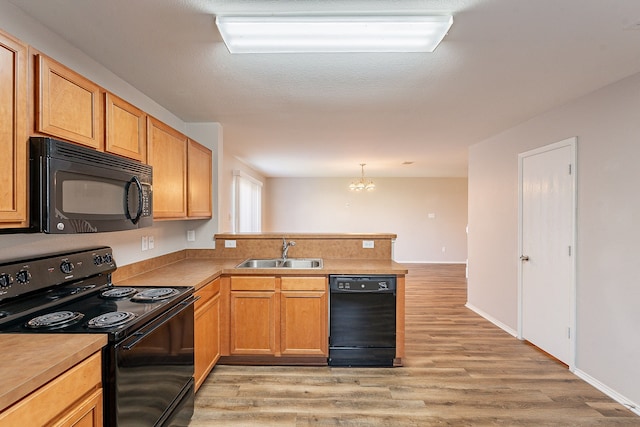 kitchen featuring black appliances, sink, decorative light fixtures, a notable chandelier, and kitchen peninsula