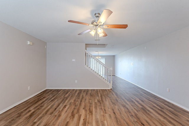 unfurnished living room featuring ceiling fan with notable chandelier and dark hardwood / wood-style flooring