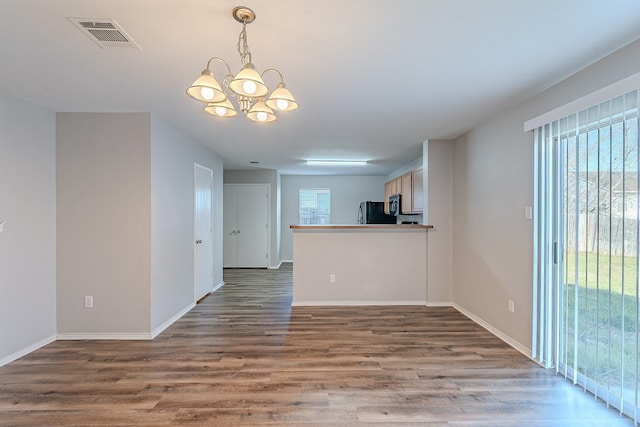 unfurnished room featuring a notable chandelier, a healthy amount of sunlight, and dark hardwood / wood-style floors