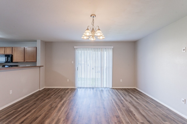 unfurnished living room with dark hardwood / wood-style floors and an inviting chandelier