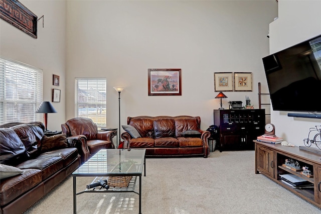 living room with a towering ceiling and light colored carpet