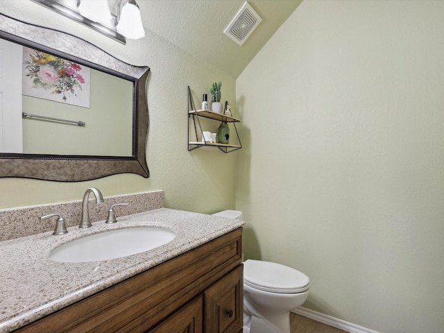 bathroom featuring vanity, vaulted ceiling, and toilet