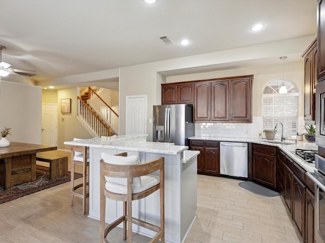 kitchen featuring a center island, sink, stainless steel appliances, backsplash, and pendant lighting