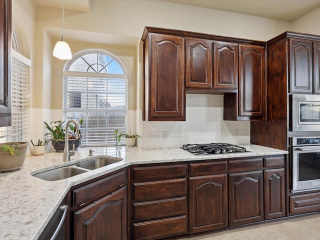 kitchen with pendant lighting, sink, appliances with stainless steel finishes, tasteful backsplash, and dark brown cabinets