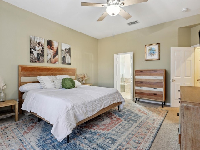 bedroom featuring ceiling fan, light colored carpet, and connected bathroom